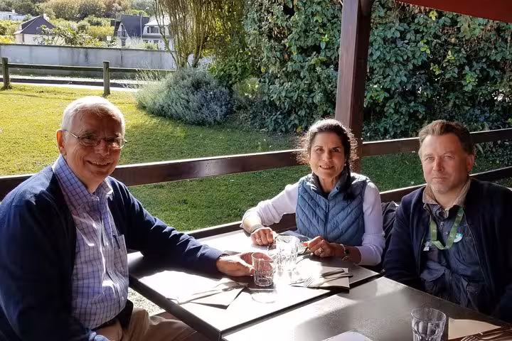 Three travelers enjoying lunch at an outdoor restaurant terrace near Mont Saint-Michel during a private tour from Le Havre