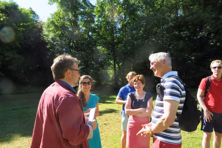Tour guide leading a group discussion outdoors in a lush green park in Brittany, France