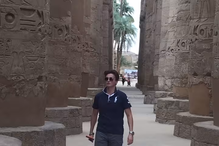 Traveler walking between towering Karnak Temple columns in Luxor on a private day trip from Hurghada