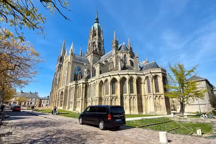Bayeux Cathedral with a private black van parked outside on a sunny day in Normandy, France