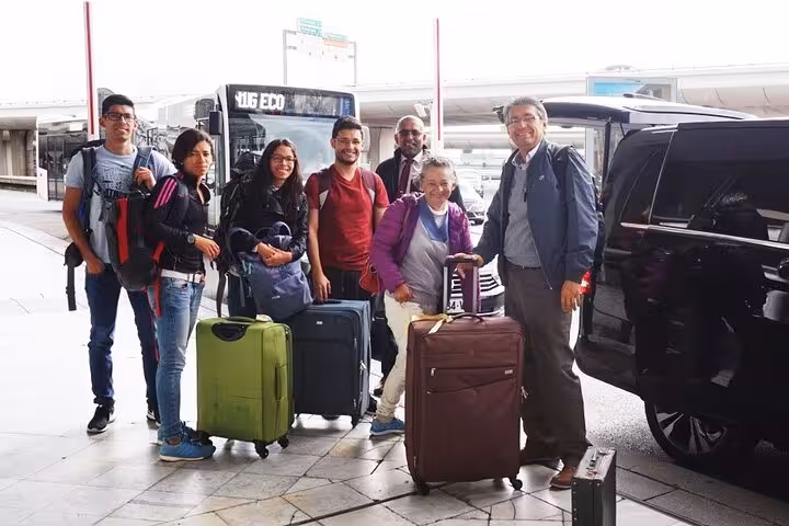 Group of travelers with luggage ready for private transfer from Errachidia to Merzouga Desert, standing by a van.