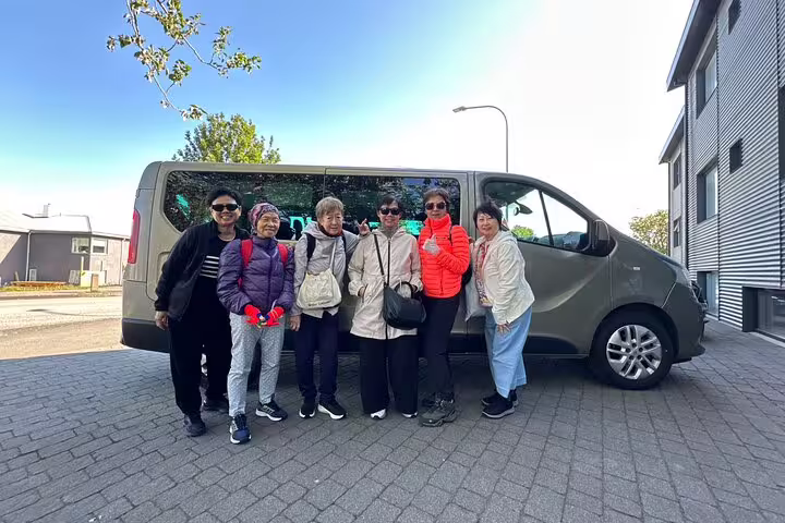 Group of six tourists posing in front of a private transfer van in Reykjavik, Iceland