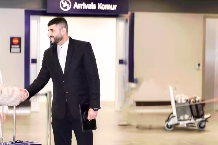 Suited driver shaking hands with arriving passenger at Keflavik Airport arrivals hall