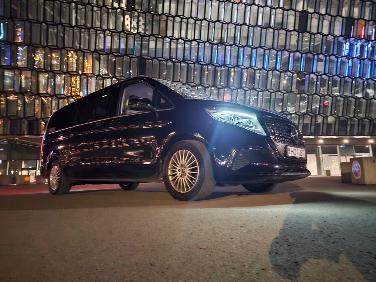 Black Mercedes V-Class van parked outside Harpa Concert Hall in Reykjavik at night
