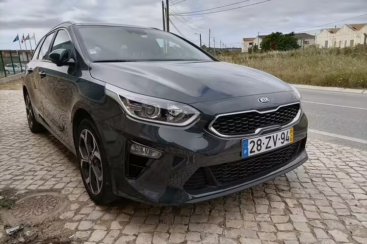 Front view of a sleek gray Kia car parked on a cobblestone street, ideal for private transfers in Faro and beyond.