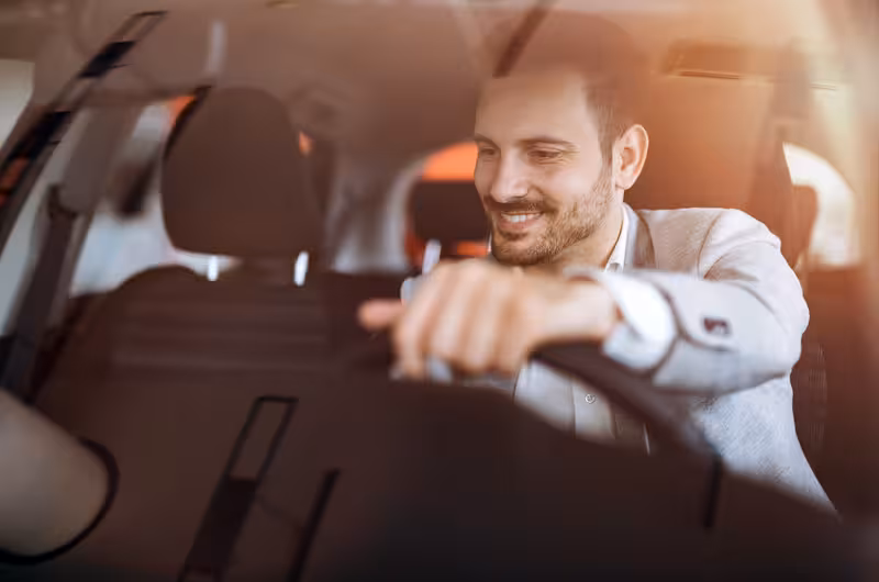Smiling driver in a sleek car providing a private transfer service from Lisbon Airport to hotel, ensuring a smooth ride.