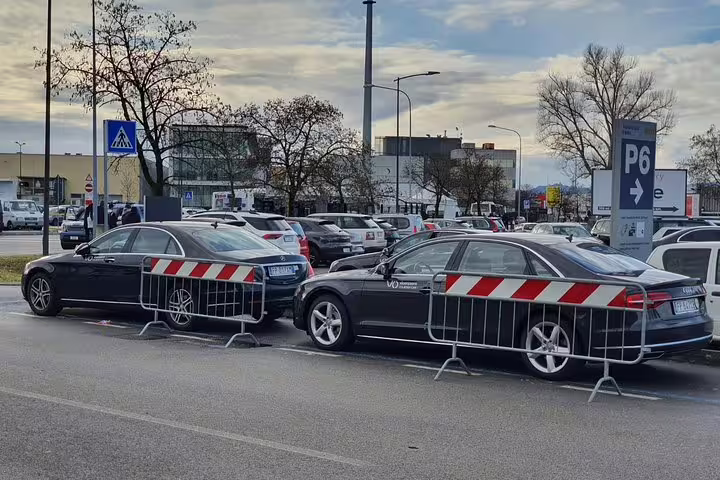 Black luxury sedans parked behind red and white safety barriers at Munich Airport parking area P6