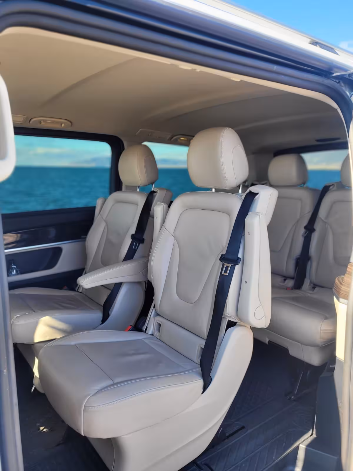 Luxury beige leather interior seating of private transfer van with ocean views through windows