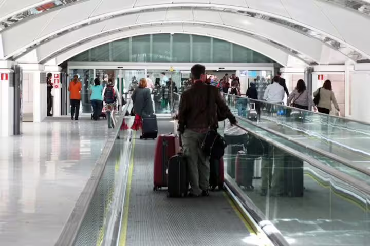 Travelers with luggage on walkway at Madrid Atocha, ideal for private hotel pickup transfer to station