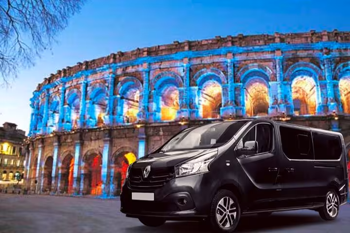 Private transfer Marseille to Nîmes van parked by Nîmes Arena at dusk, premium door-to-door service