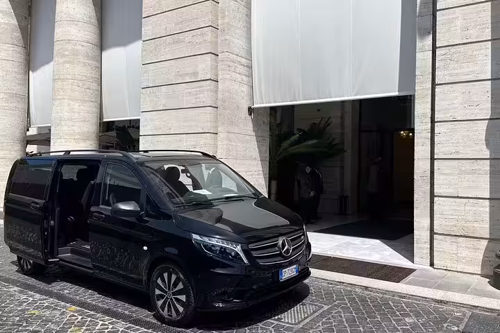 Luxurious black Mercedes van ready for private transfer from Naples to Sorrento, parked outside a grand building.