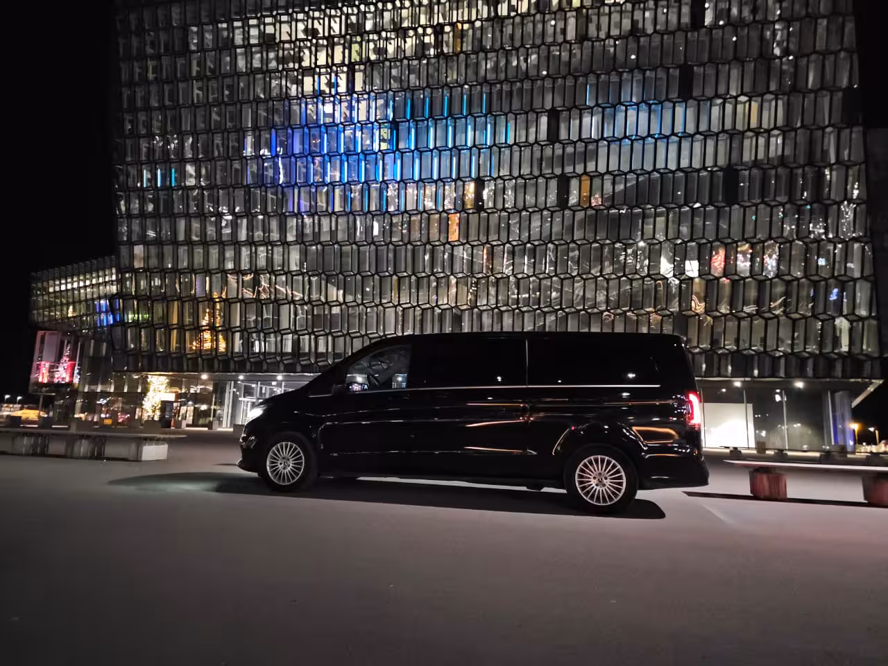Black Mercedes V-Class van parked outside Harpa Concert Hall in Reykjavik at night
