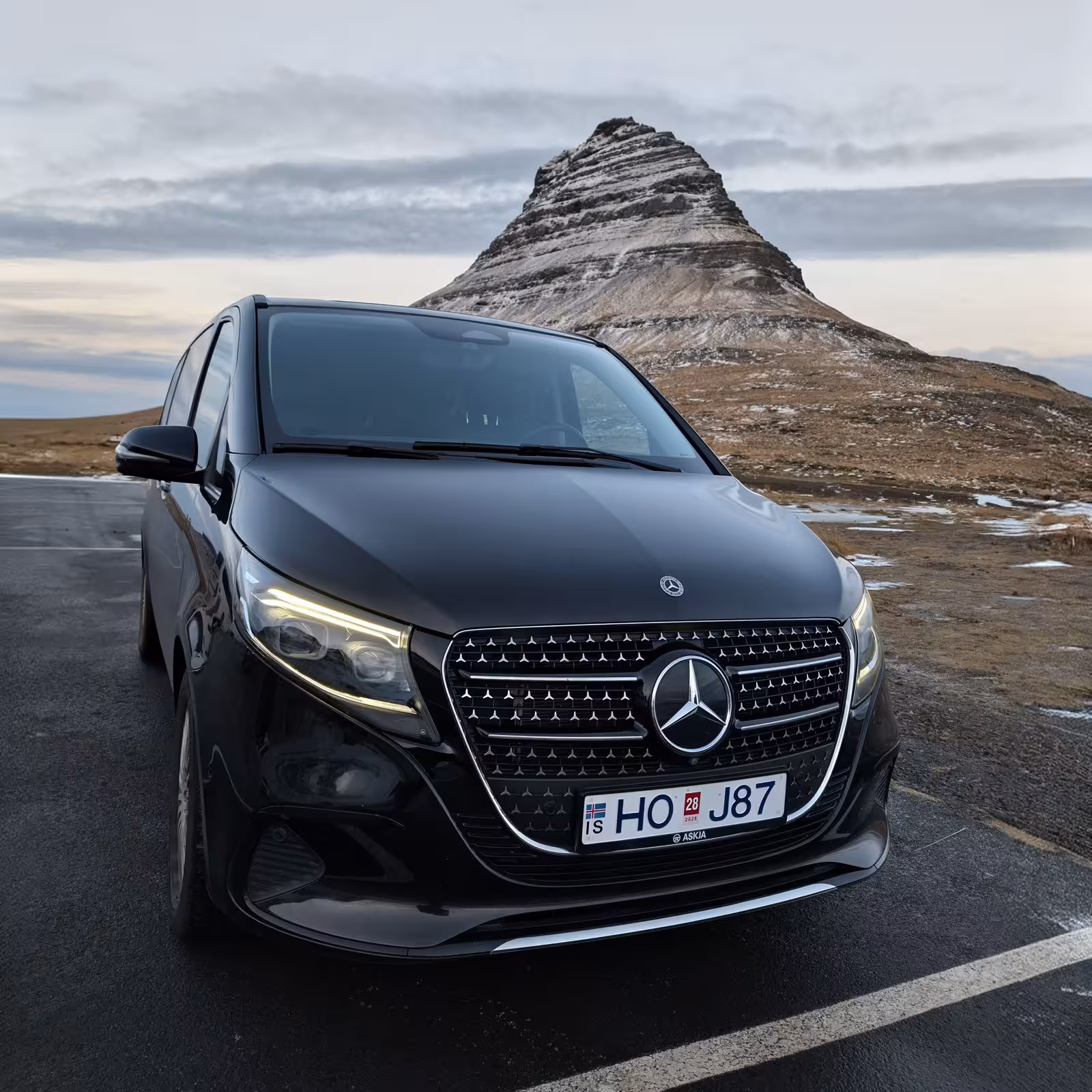 Black Mercedes-Benz V-Class minivan parked in front of Kirkjufell mountain in Iceland