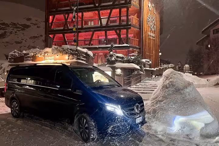 Luxurious private transfer van parked in snowy Zermatt at night, highlighting comfort and convenience for travelers.