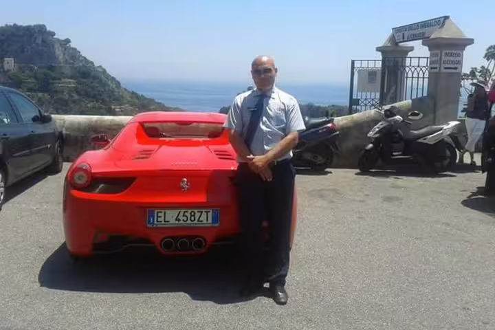 Autista privato accanto a sportiva rossa con vista mare durante transfer da Napoli a Praiano lungo la Costiera Amalfitana