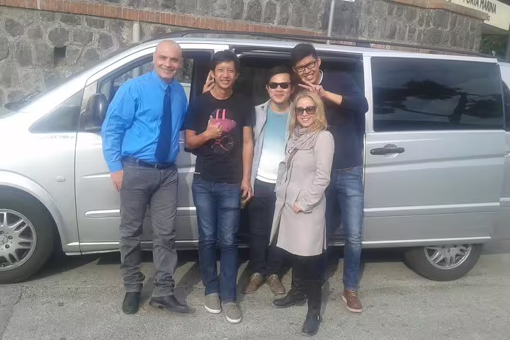Happy small group with local driver beside private minivan during Naples to Praiano transfer along the Amalfi Coast