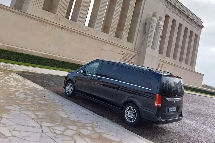 Black Mercedes-Benz V-Class van parked in front of a grand neoclassical monument in Reims