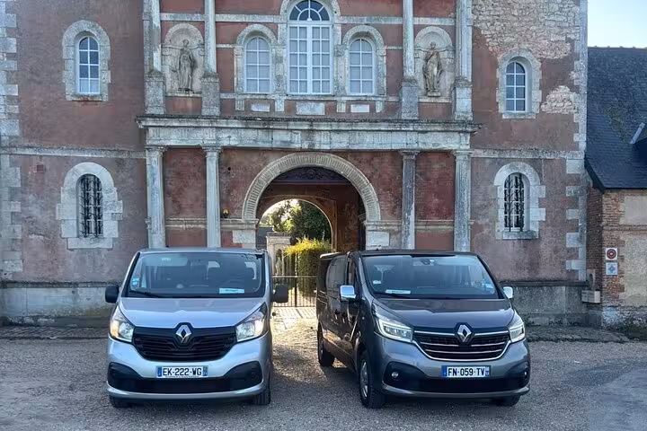 Two Renault Trafic vans parked in front of a historic French château gateway