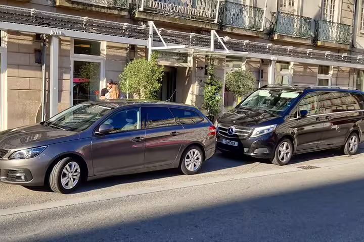 Private transfer vehicles parked outside a hotel, ready for travel from Porto to Santiago de Compostela.
