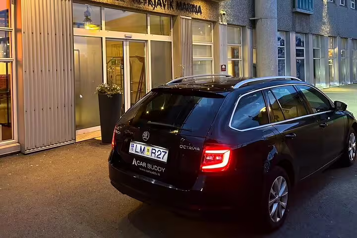 Black Skoda Octavia estate car parked outside Reykjavik Marina hotel at night