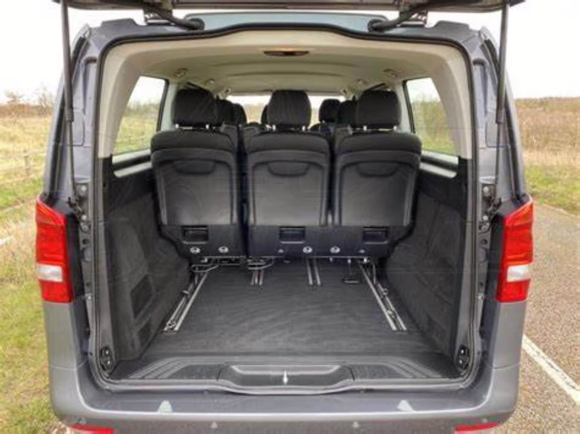 Spacious van interior with black seats and open rear cargo area for airport transfer
