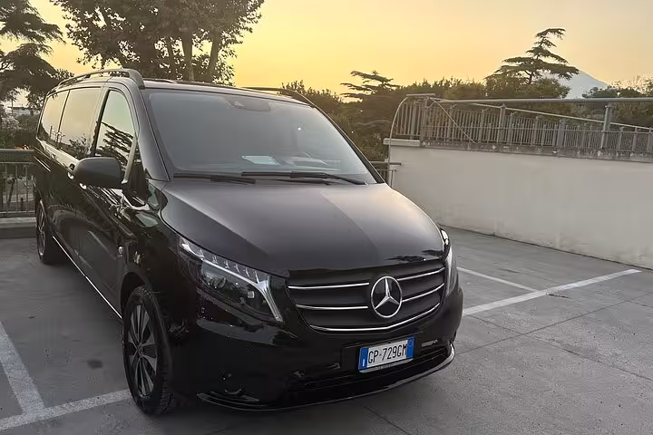 Luxurious black Mercedes van ready for private transfer from Rome to Amalfi Coast at sunset.