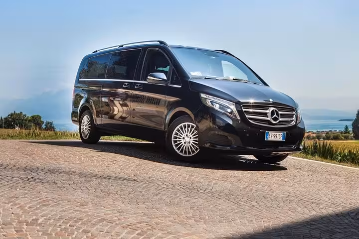 Elegant black Mercedes van for private one-way transfer from Rome Termini to city center with scenic backdrop.