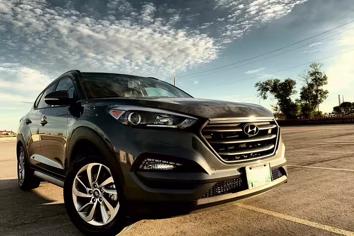 Dark gray Hyundai Tucson SUV parked in lot under dramatic cloudy sky