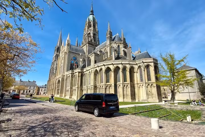 Black private van parked in front of Bayeux Cathedral, Normandy, France on a sunny day