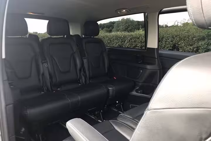 Spacious black leather interior of private transfer van with three-row seating for Paris airport transfers