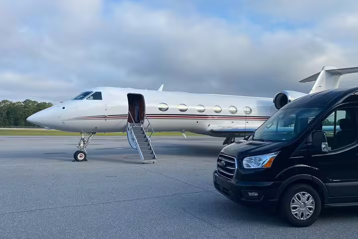 Private transfer black van parked beside a private jet at Oslo Airport for luxury ski resort transport to Trysil