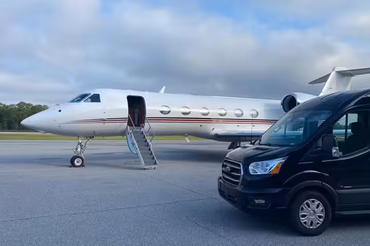 Black luxury van parked beside a private jet on airport tarmac in Puerto Vallarta