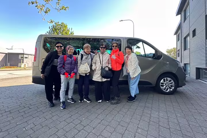Group of six tourists posing in front of a private transfer van in Reykjavik, Iceland
