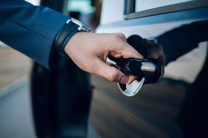 Close-up of a hand opening a car door, signifying personalized private transfer service from VCE Airport to Alta Badia.