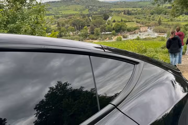 Private car parked with scenic view of Terme di Saturnia, highlighting luxurious transport to Italy's thermal springs.