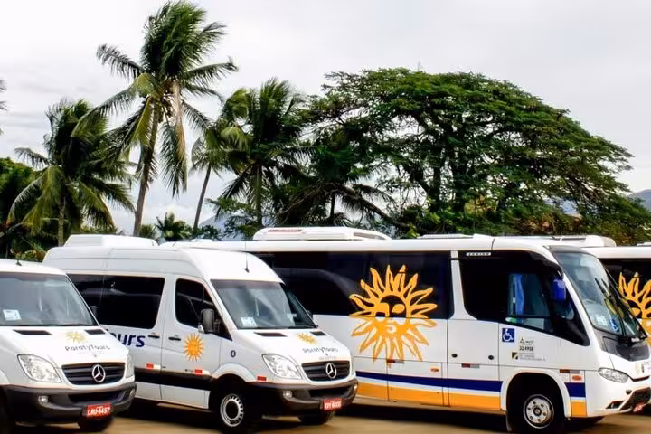 Fleet of private transportation vans ready for travel from Búzios to Rio de Janeiro with palm trees in the background.