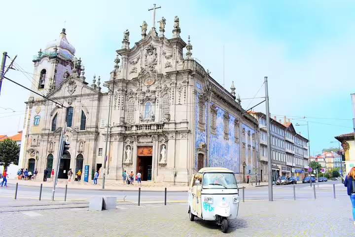 Tuk tuk parked in front of the ornate Igreja do Carmo in Porto, perfect for a full-day private city tour experience.