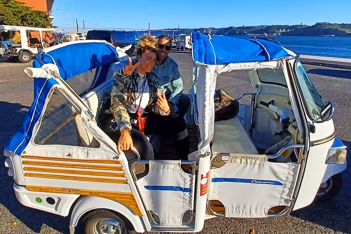 Couple enjoying a 4-hour private tuk tuk tour in Lisbon near the Tagus waterfront, fun city sightseeing