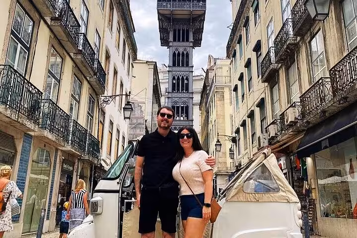 Private tuk tuk tour in Lisbon at Santa Justa Lift, couple posing in Baixa on 4-hour ride