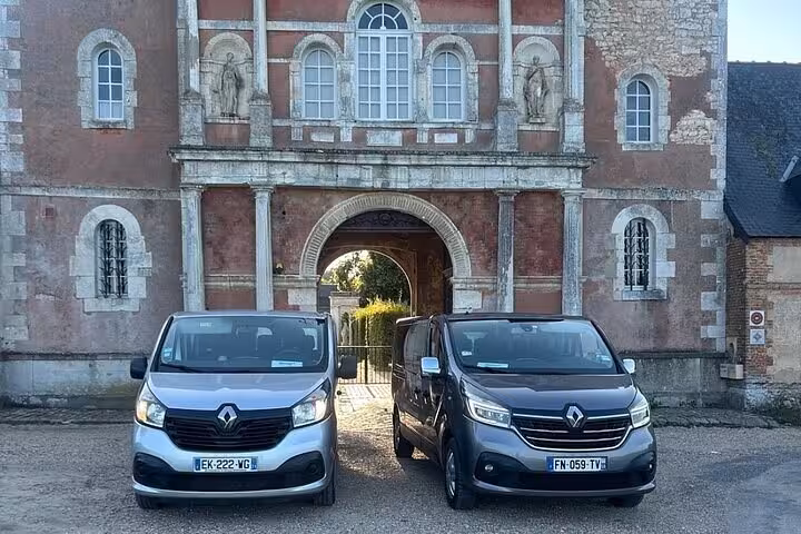 Two Renault vans parked in front of a historic French château gateway in Normandy