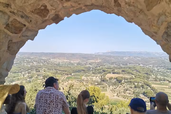 Private vehicle with driver in Provence stops at hilltop viewpoint framed by stone arch over Luberon valley