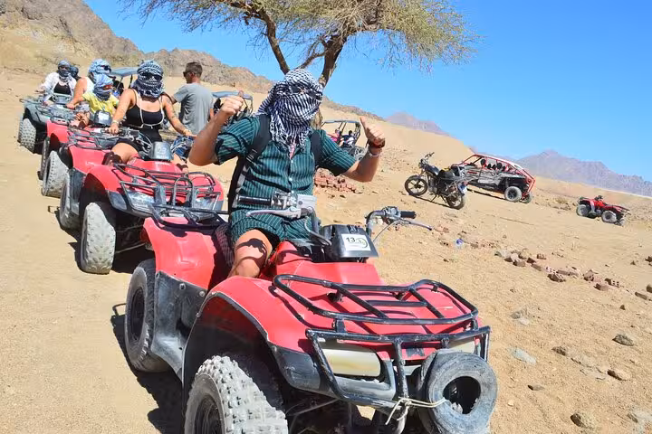 Group on red quad bikes during private VIP Sharm El Sheikh ATV desert adventure with guide and buggies