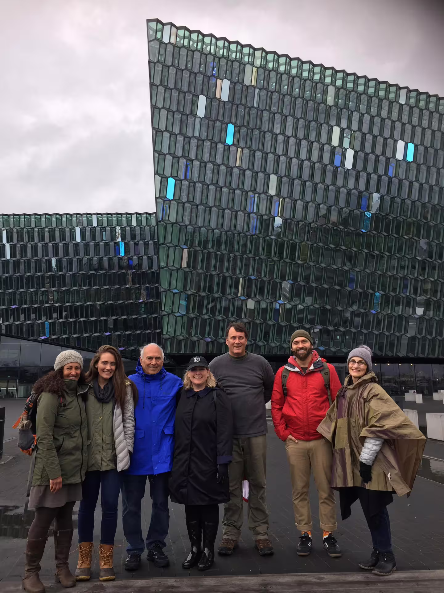Group of seven tourists posing in front of Harpa Concert Hall during a private walking tour in Reykjavik