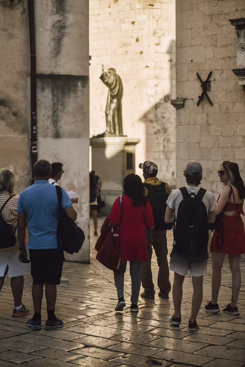 Small group exploring an old town square at sunset on a private walking tour with a local guide and landmarks
