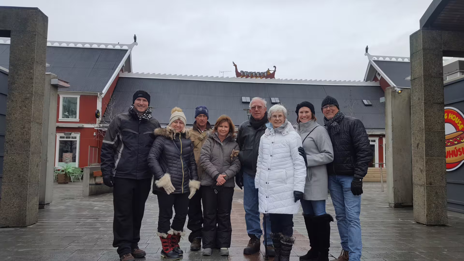 Group of eight tourists in winter coats posing outdoors during a private walking tour of Reykjavik town