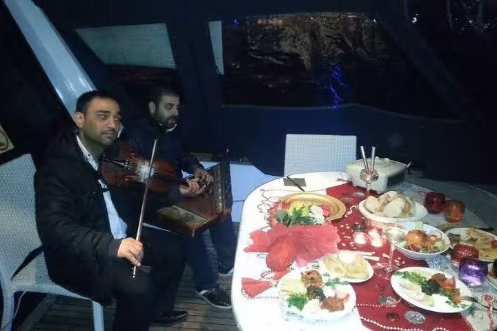 Live violin music beside a decorated dinner table on a private yacht for birthday or anniversary celebration