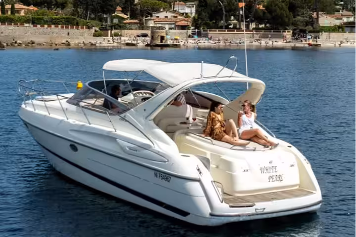White luxury yacht White Pearl with guests relaxing on bow in Cannes harbor on sunny day