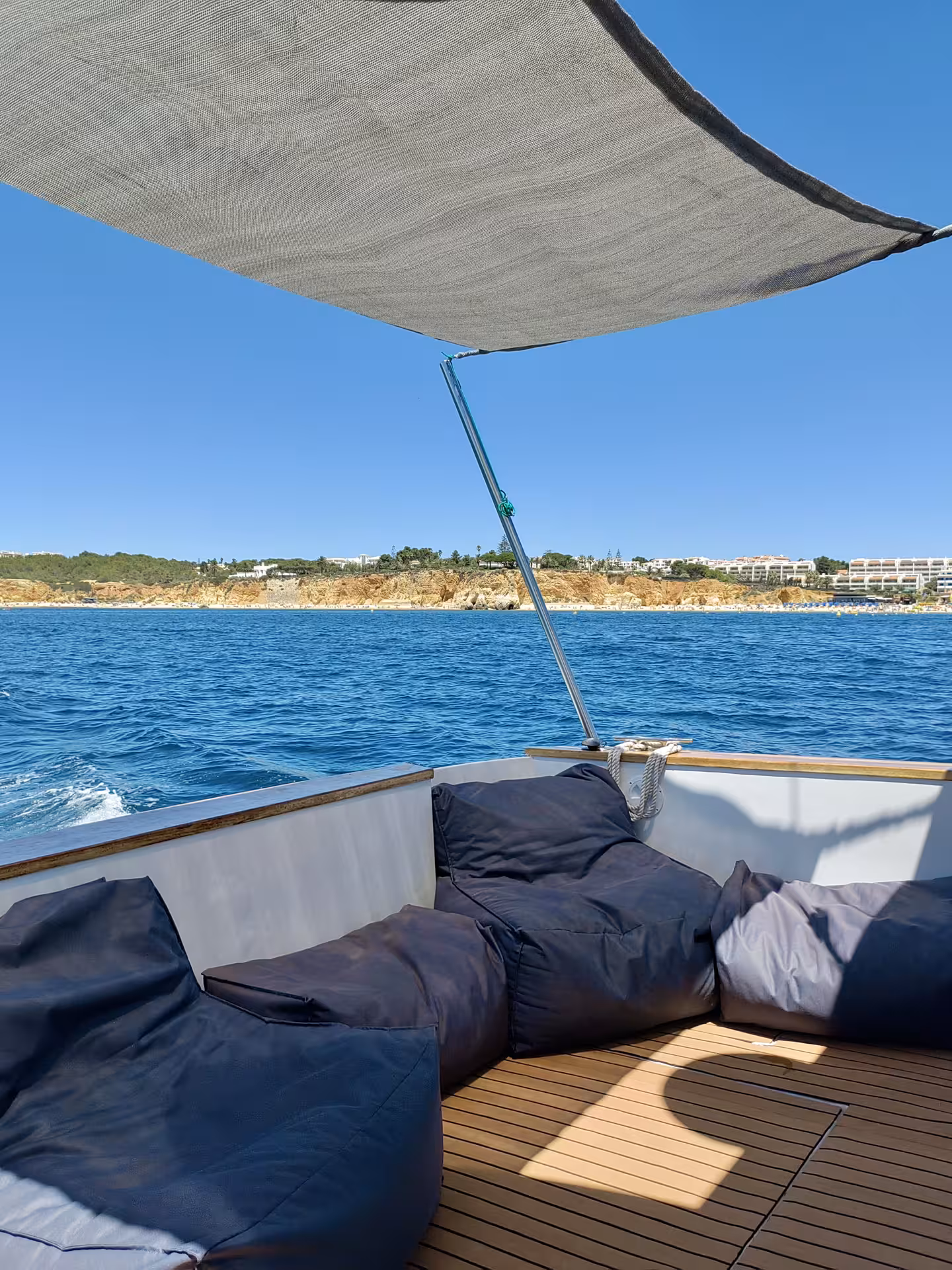 Relaxing seating area with bean bags under a sunshade on a private yacht, offering serene ocean views.