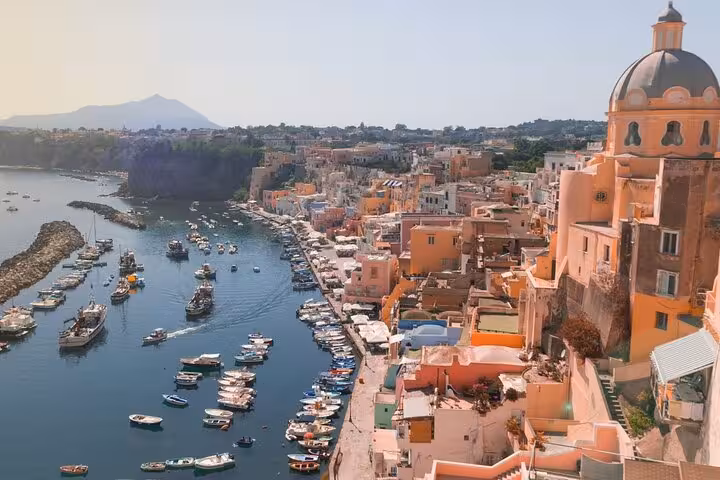 Colorful buildings and boats along Procida's vibrant coastline, showcasing the charm of a Naples boat tour.