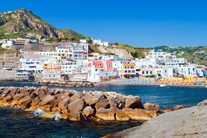Colorful seaside village on Procida Island with rocky shoreline, featured in Naples boat tour itinerary.